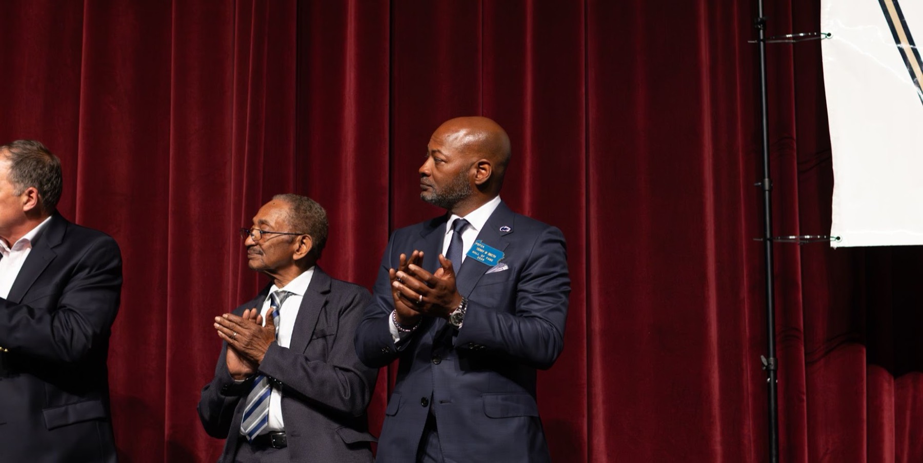 Speakers applauding on stage at a banquet